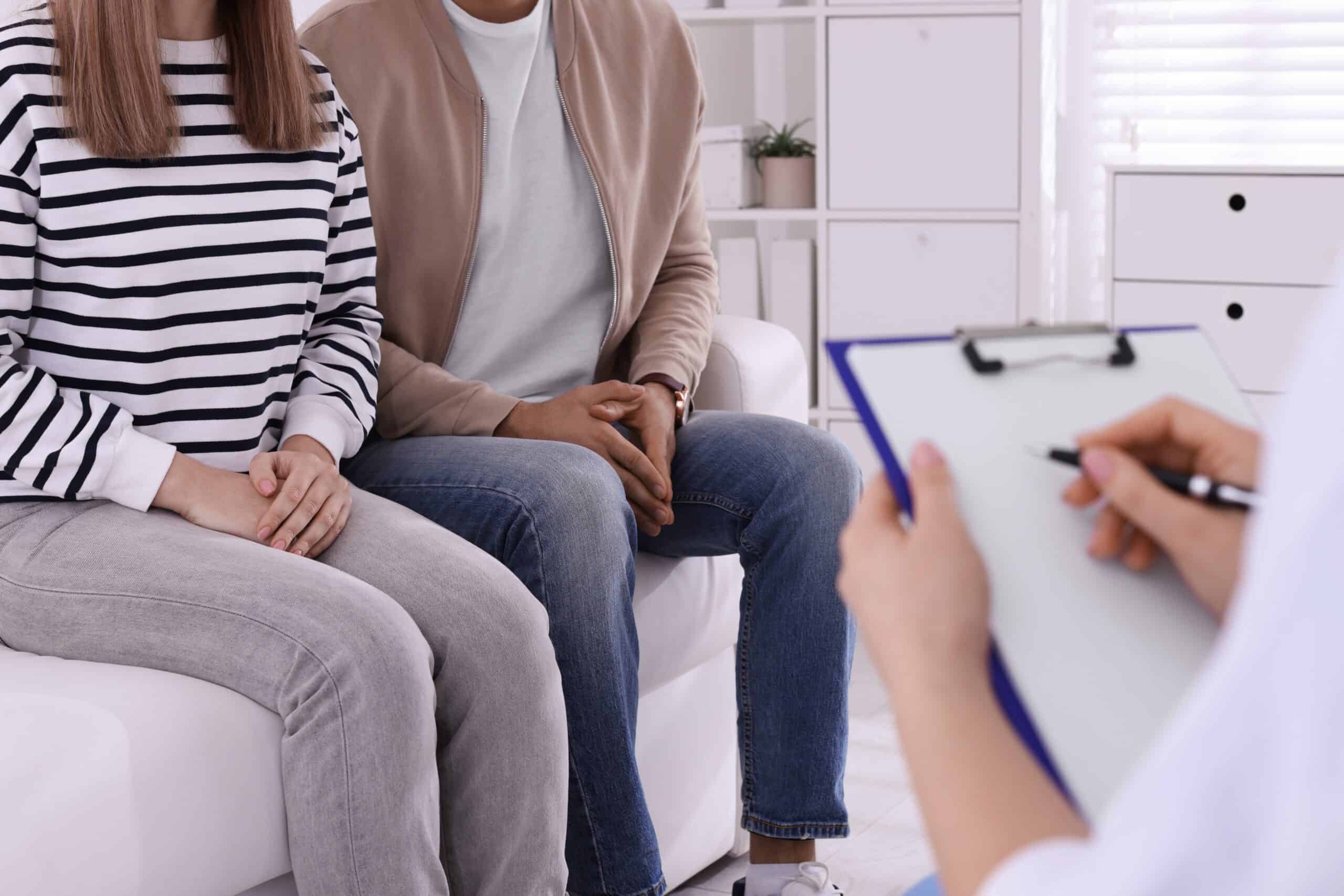 Man and woman sitting on a couch with a doctor discussing documents, highlighting the difference between STI vs STD