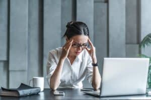 Woman holding her head in pain, eyes closed, expressing discomfort from a migraine.