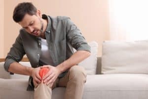 Image showing a person holding their knee in discomfort, indicating knee pain.