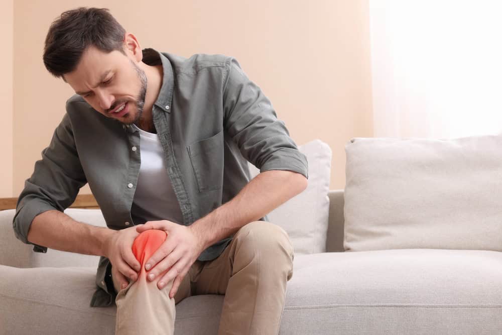 Image showing a person holding their knee in discomfort, indicating knee pain.