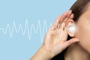 A person holding their hand near the ear with sound waves illustrated, symbolizing tinnitus and hearing issues.