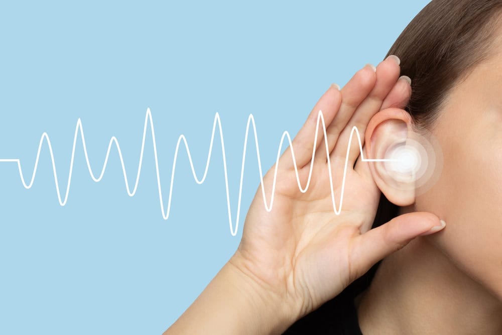 A person holding their hand near the ear with sound waves illustrated, symbolizing tinnitus and hearing issues.